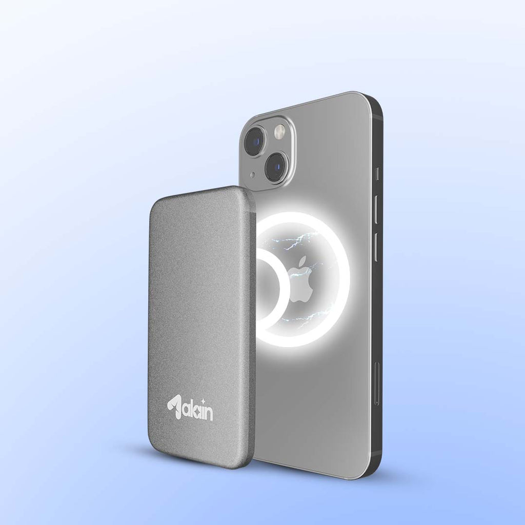 Magnetic wireless power bank attached to the back of a silver smartphone with camera lenses