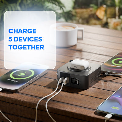 Multi-device power bank charging smartphones and earbuds on a wooden table outdoors